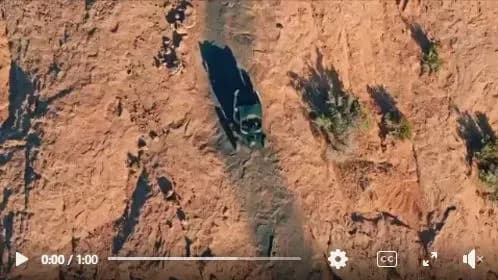 Overhead drone view of a UTV driving a sandy trail through red desert scrub