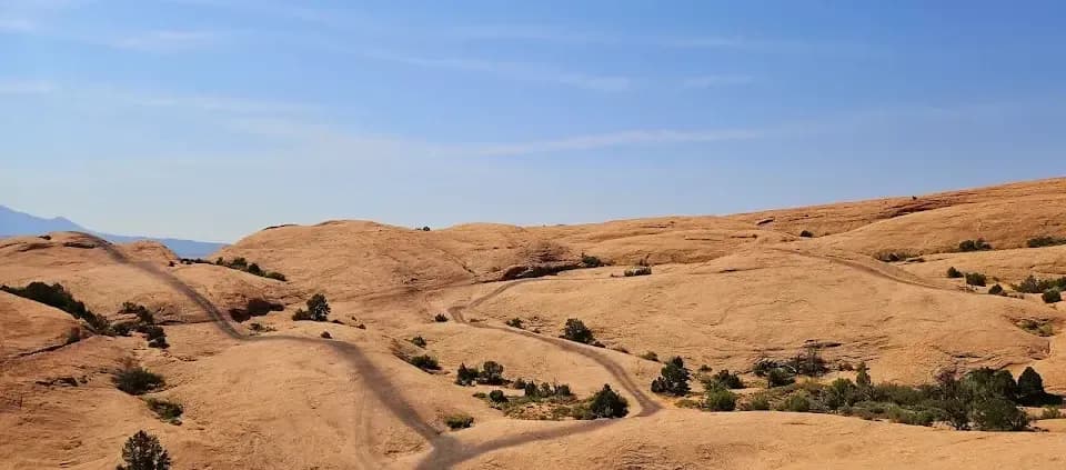 Winding dirt UTV trail cutting across open red-rock desert near Moab