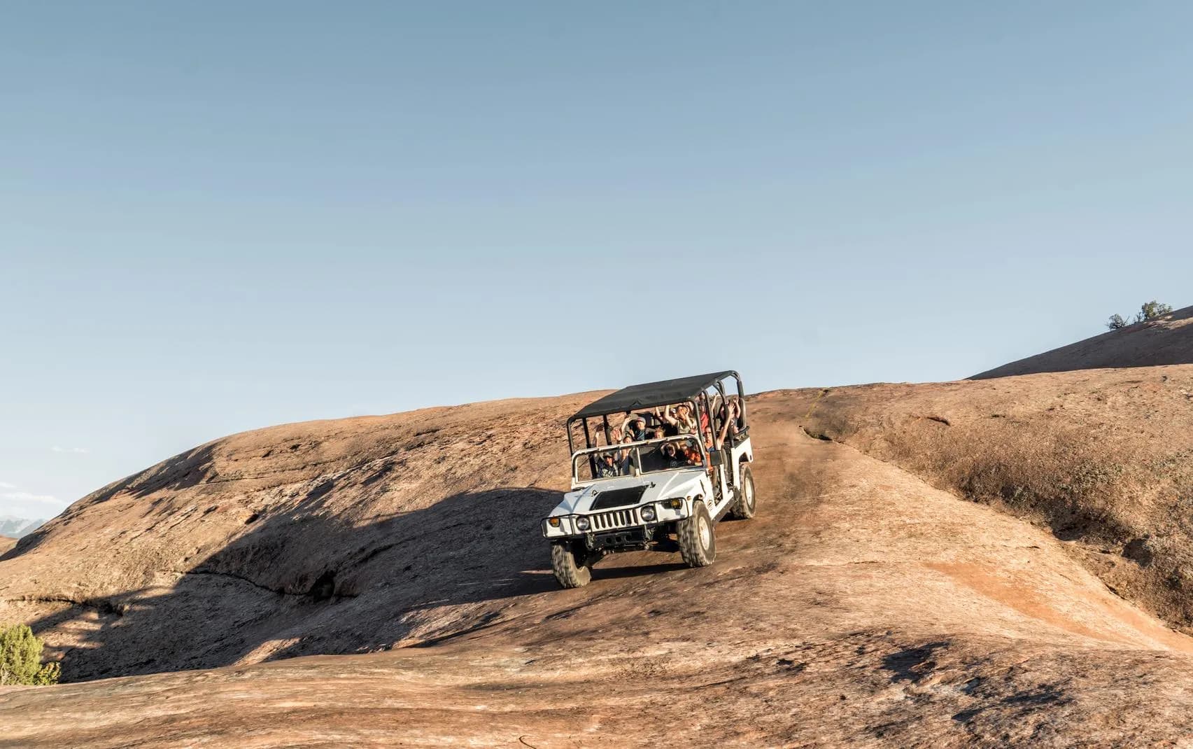 White Hummer climbing a steep slickrock sandstone formation