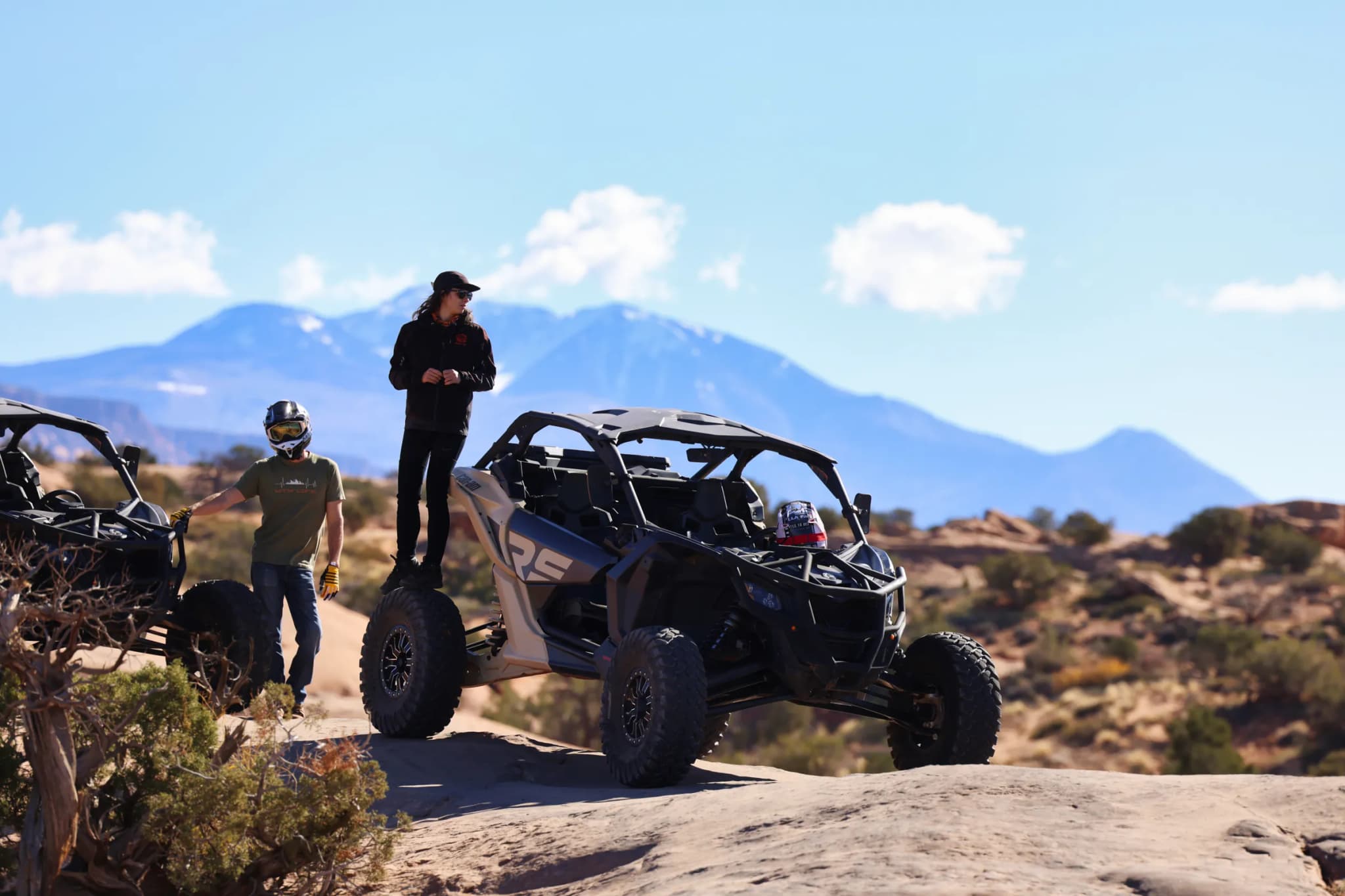 Guides standing beside Can-Am UTVs on the slickrock below the snow-capped La Sal Mountains