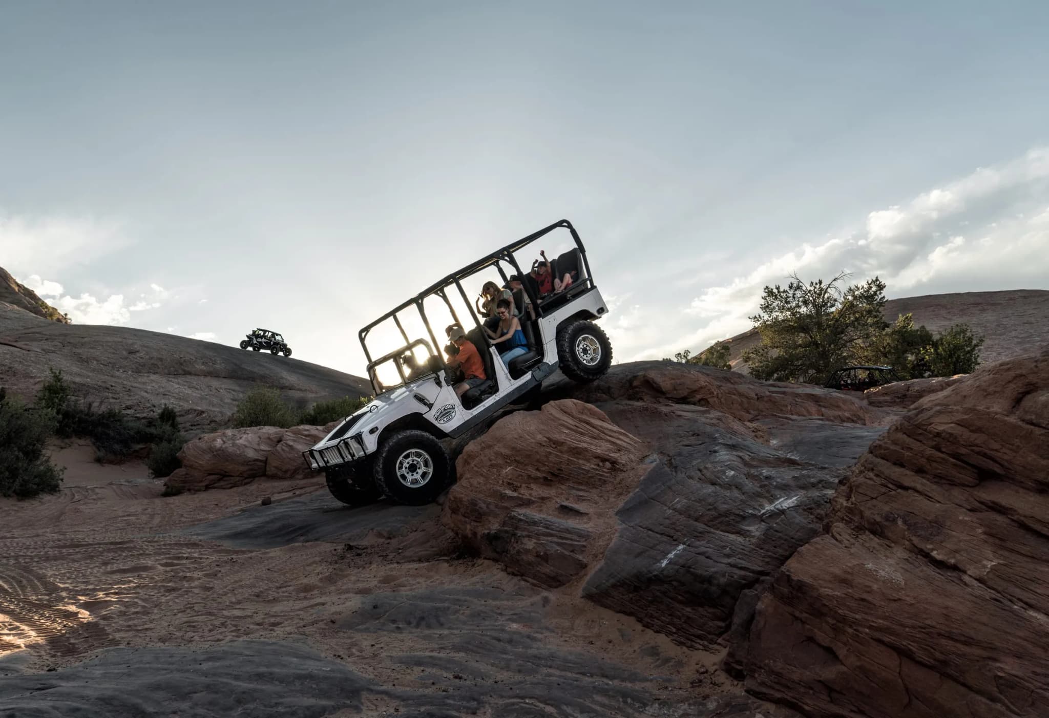 White Hummer parked atop a slickrock dome at Hell's Revenge with red rock domes and distant mountains behind