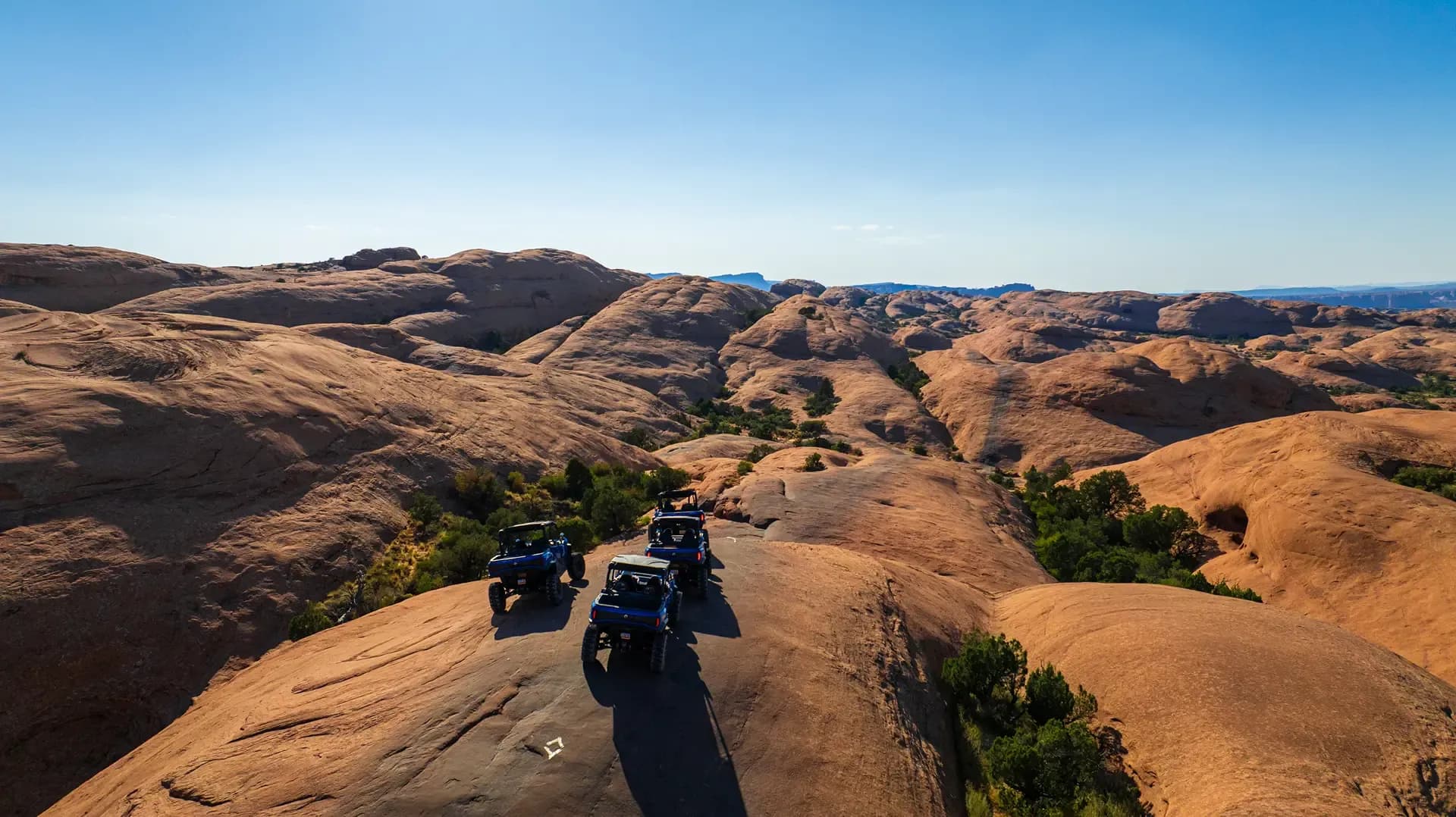 Drone view of two side-by-sides cresting a slickrock fin on Hell's Revenge