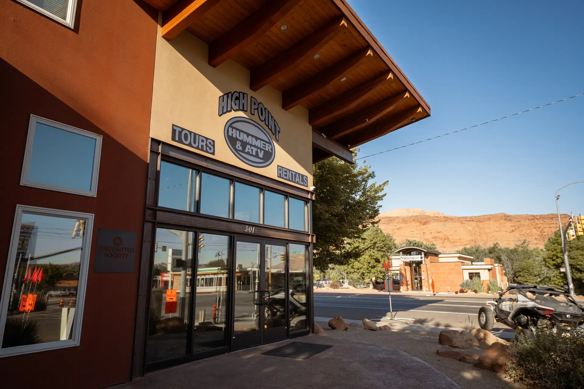 Close-up of the High Point Hummer & ATV storefront sign with red rock cliffs behind