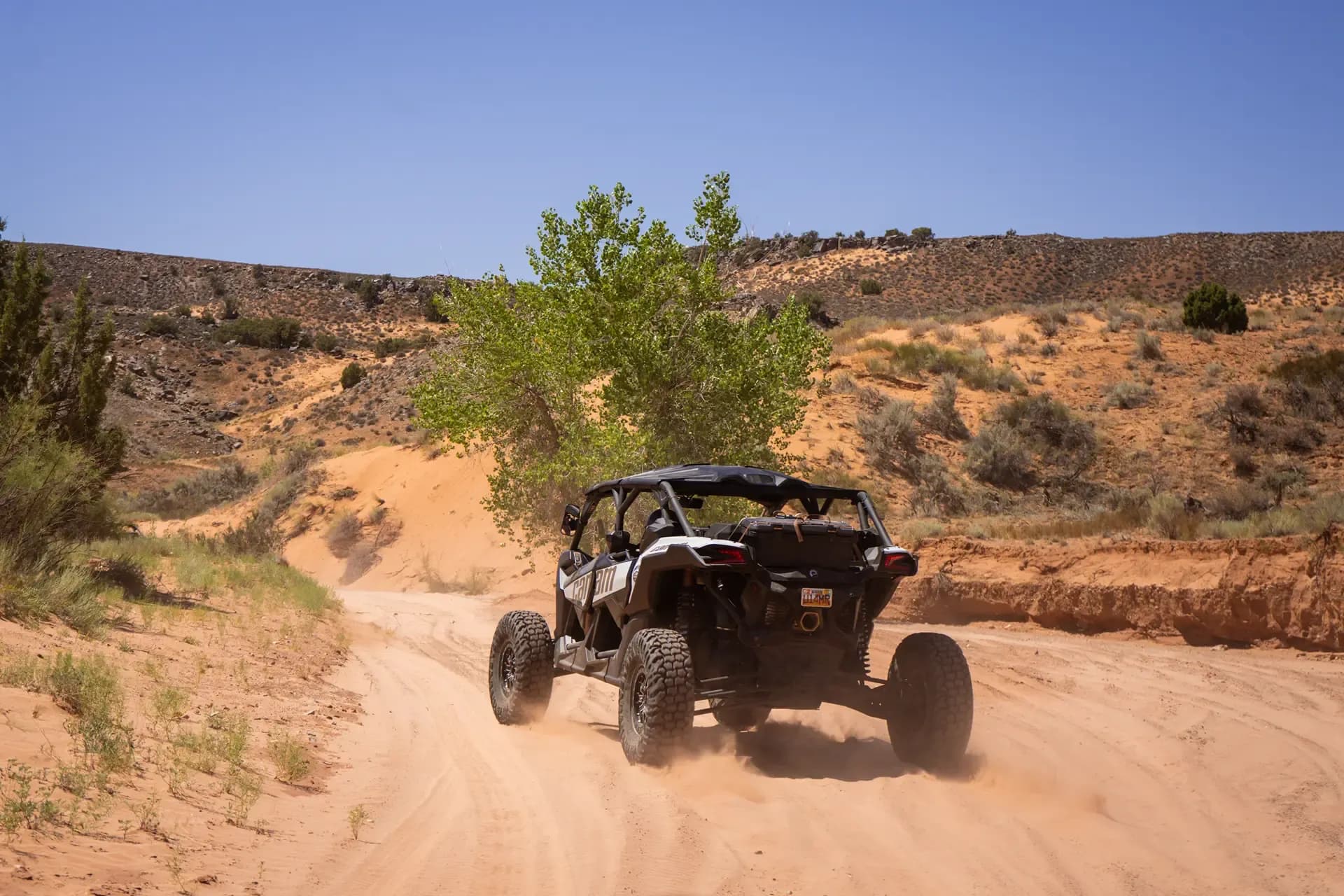 Can-Am Maverick X3 Max kicking up sand as it climbs a desert trail