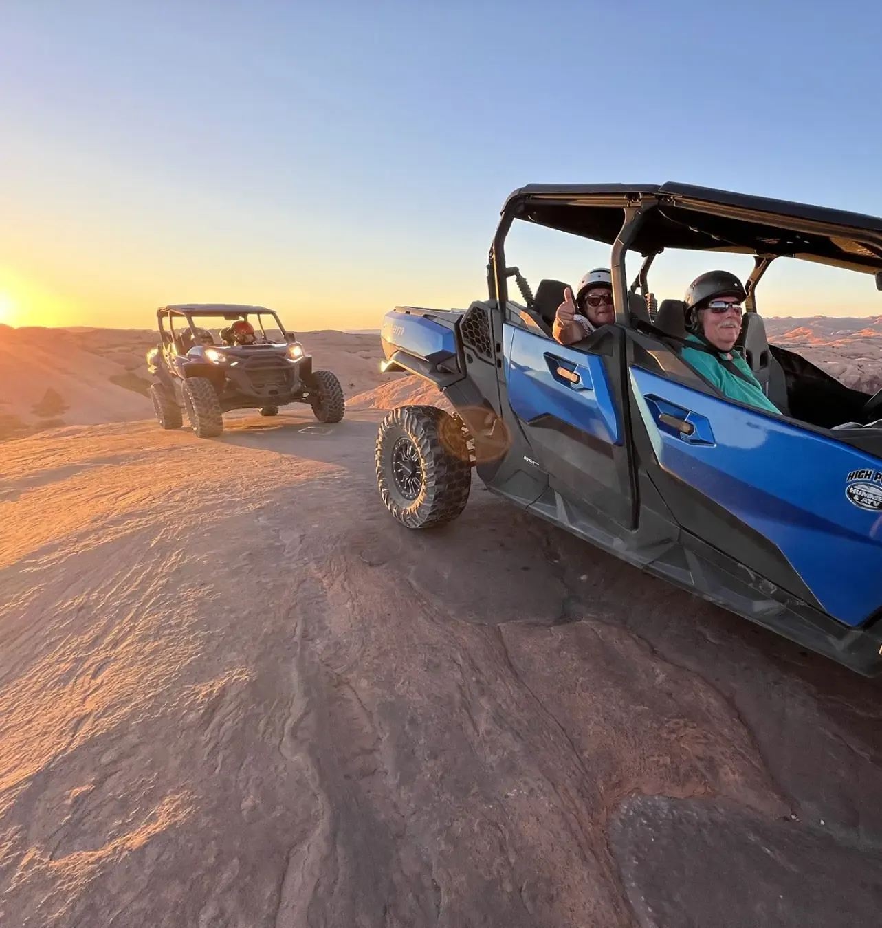 UTVs on rocky terrain at sunset.