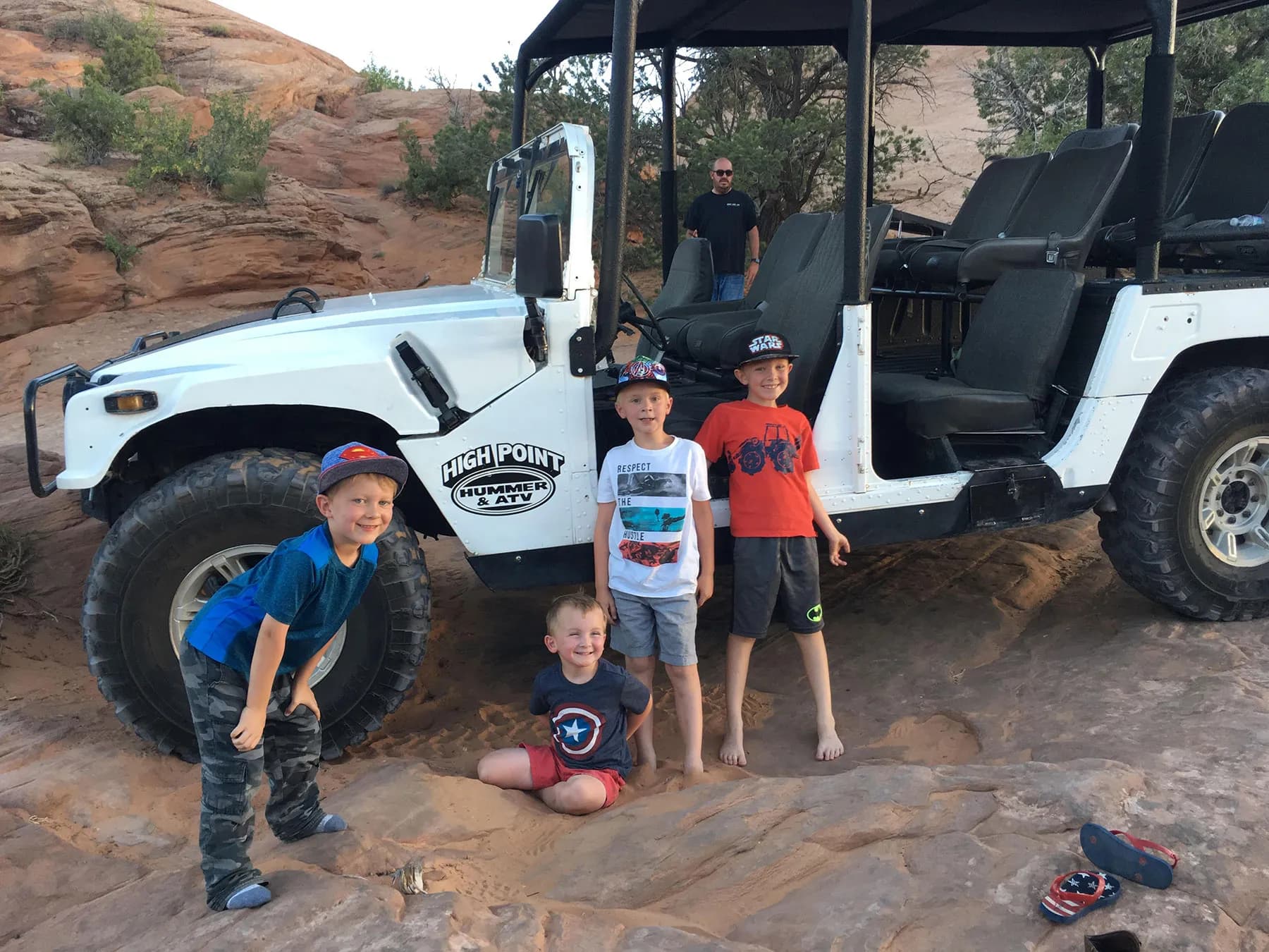 Three young boys posing beside a white High Point Hummer on the slickrock