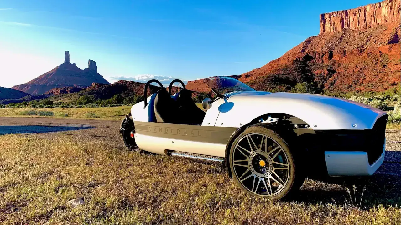 Vanderhall Venice roadster parked on grass below Castleton Tower and red mesas