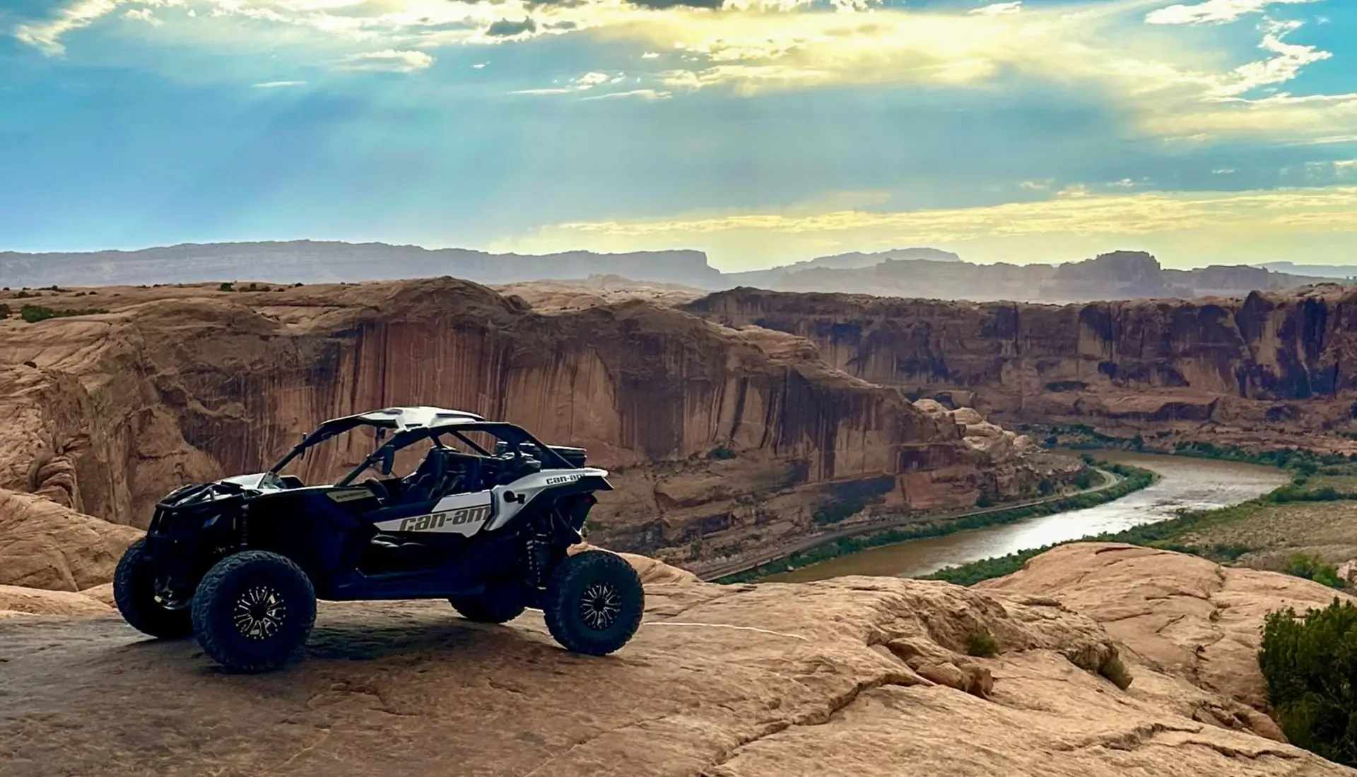 Can-Am Maverick X3 parked on a rim above the Colorado River canyon under a dramatic sky