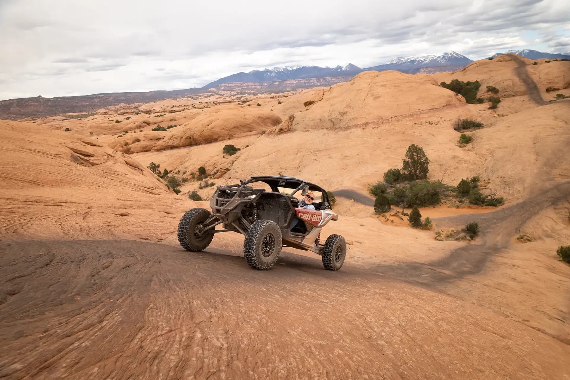 Can-Am side-by-side crossing open slickrock with the La Sal Mountains behind