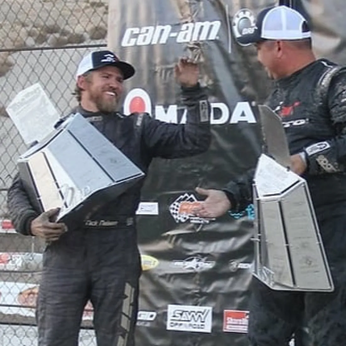 Off-road racers celebrating with trophies on a Can-Am race podium