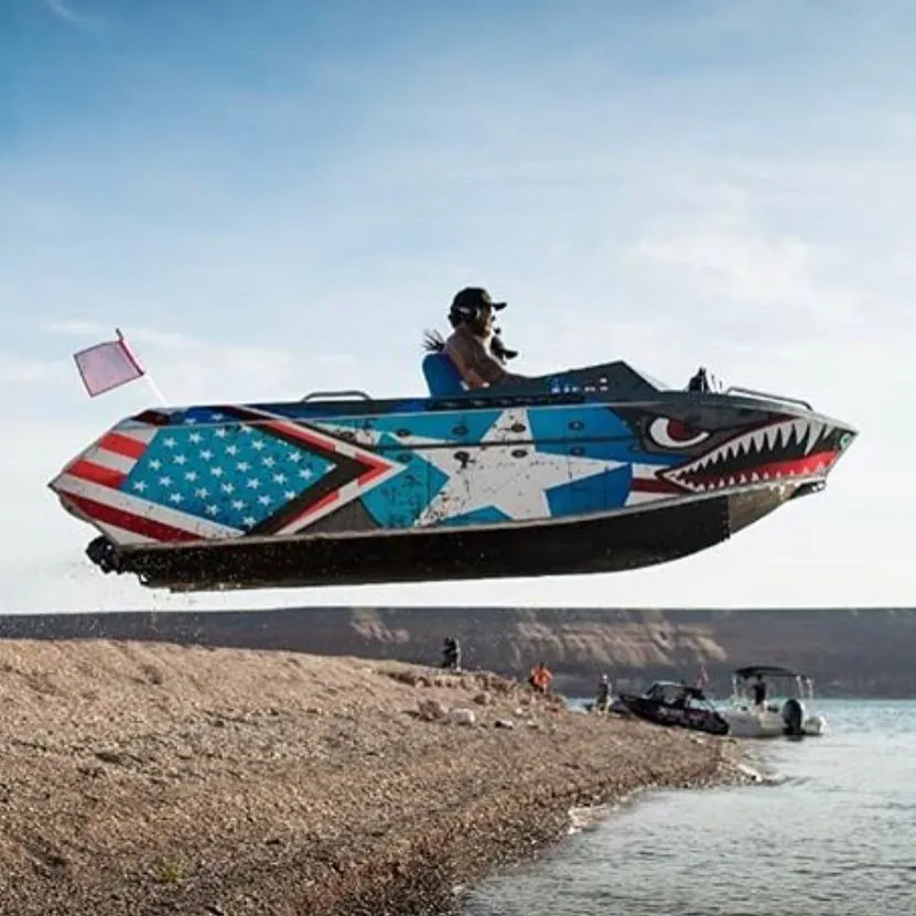 Jet boat painted with an American flag and shark teeth racing along the shoreline