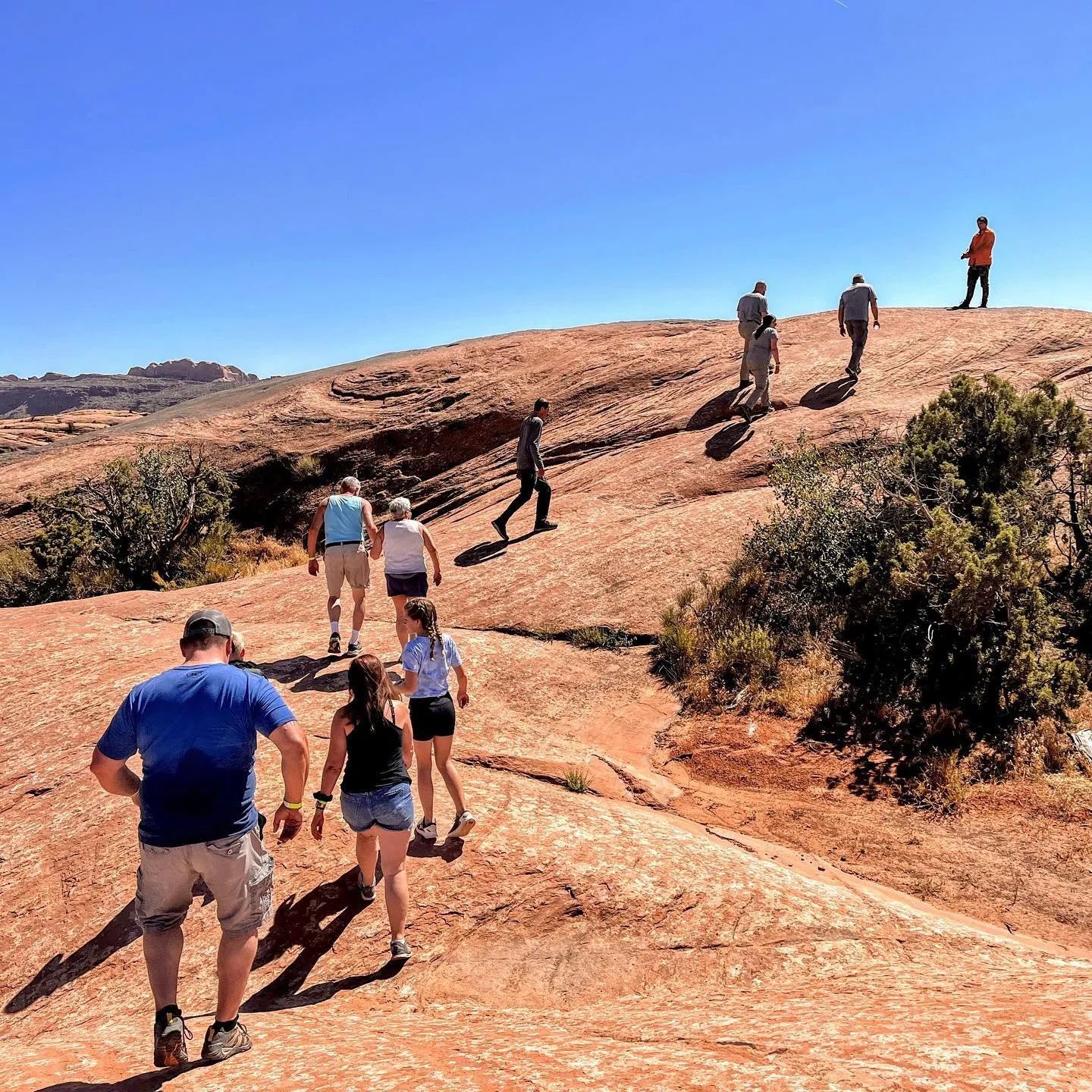 Tour group walking up a slickrock dome during a guided stop
