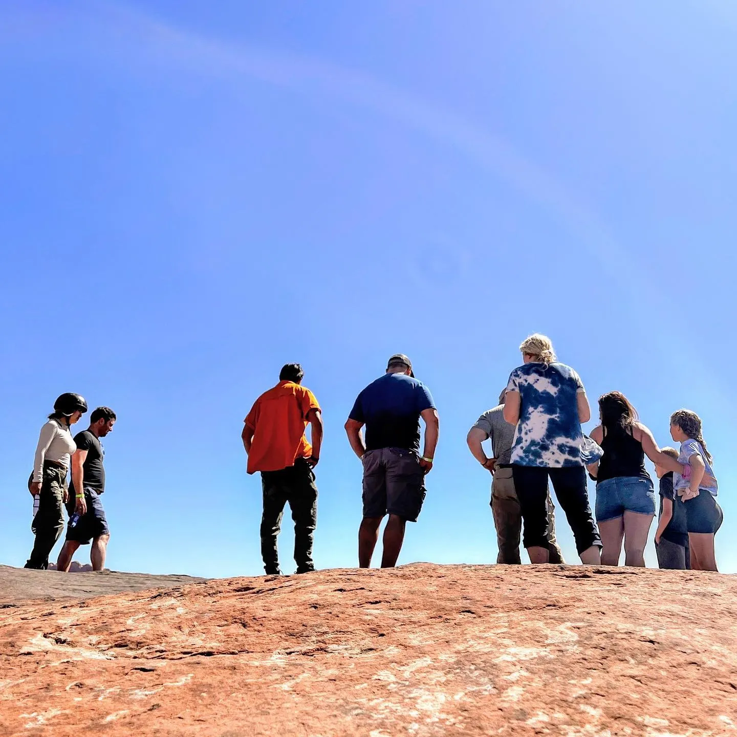 Tour group standing on top of a slickrock ridge against a blue sky