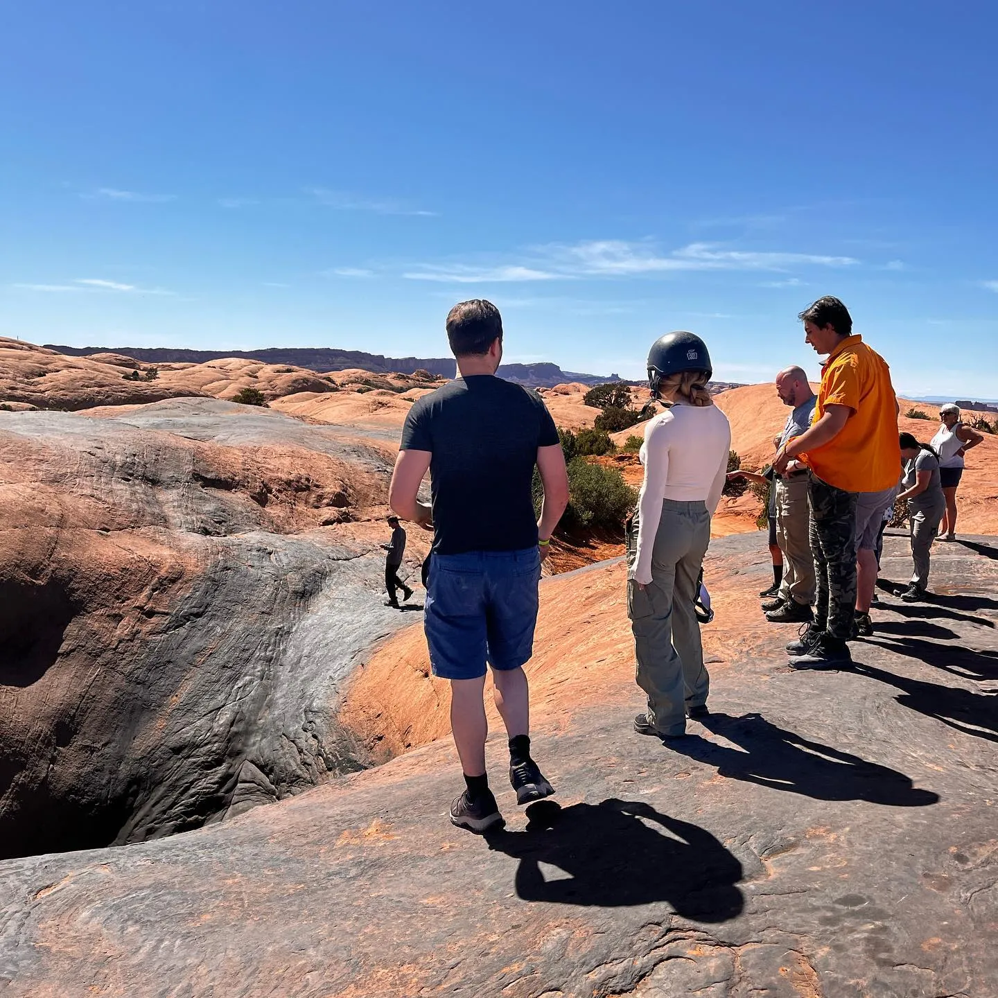 Guide and guests looking into a slickrock bowl during a tour stop