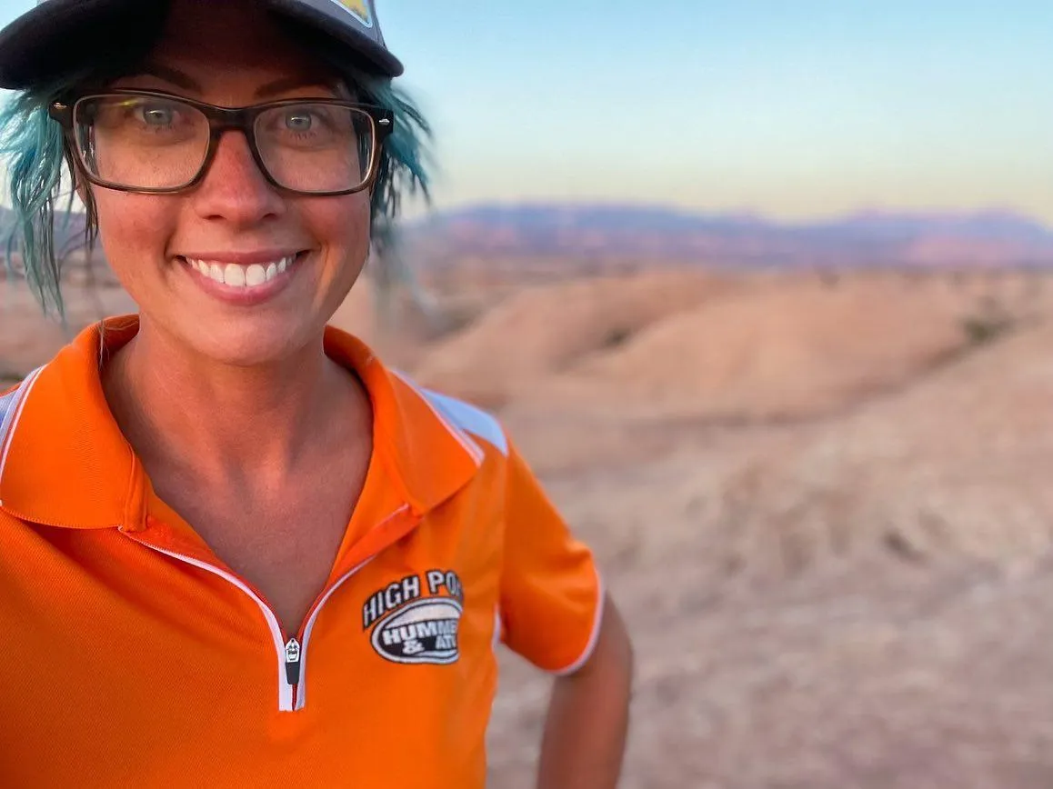 Guide Lindsay smiling in her orange High Point polo on the slickrock