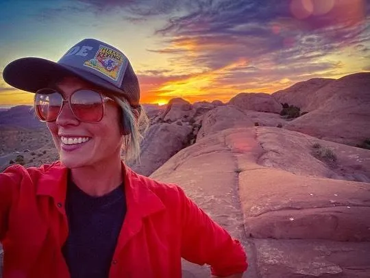 High Point Hummer tour guide smiling on red slickrock at golden hour