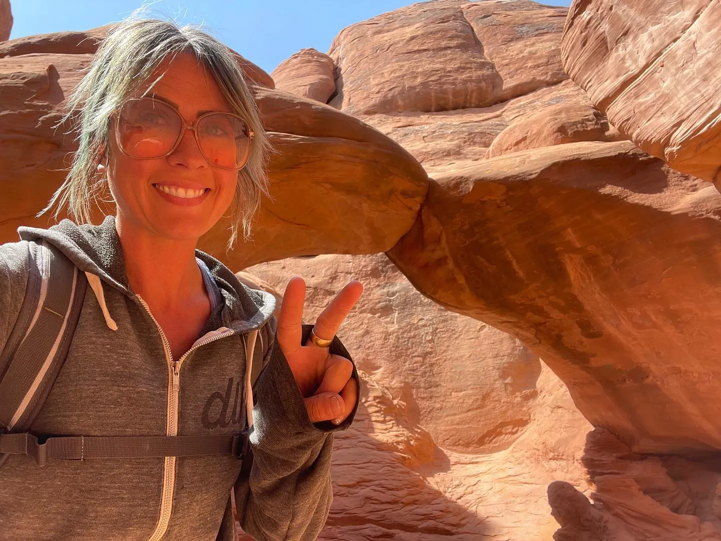 Guide Lindsay making a peace sign beneath a red-rock arch