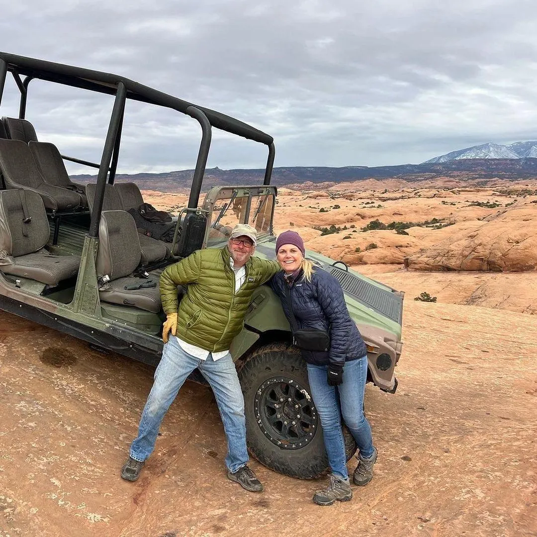 Couple posing beside an open-top Hummer on the slickrock
