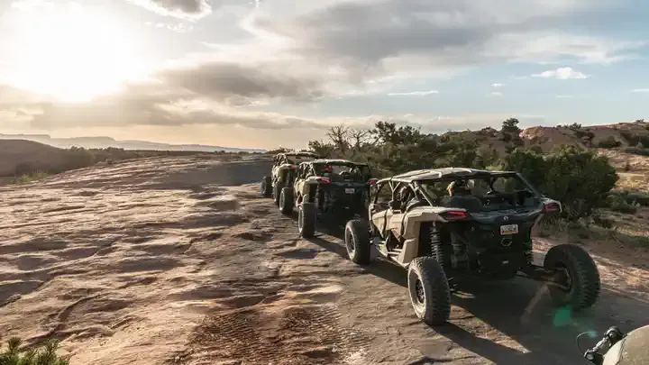 Line of Can-Am UTVs parked on the slickrock at sunset