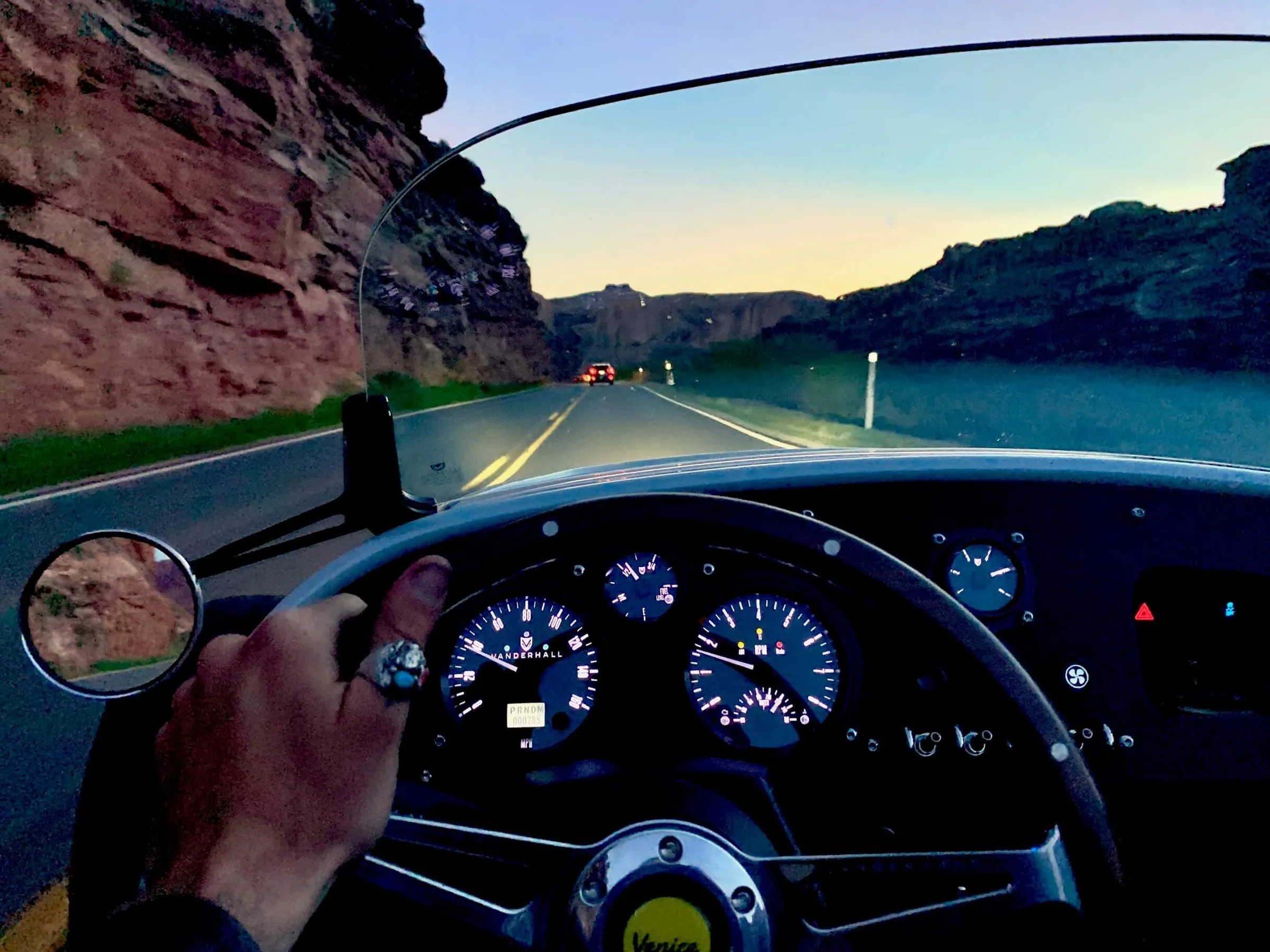 Driver's view from a Vanderhall cruising a red-rock canyon road