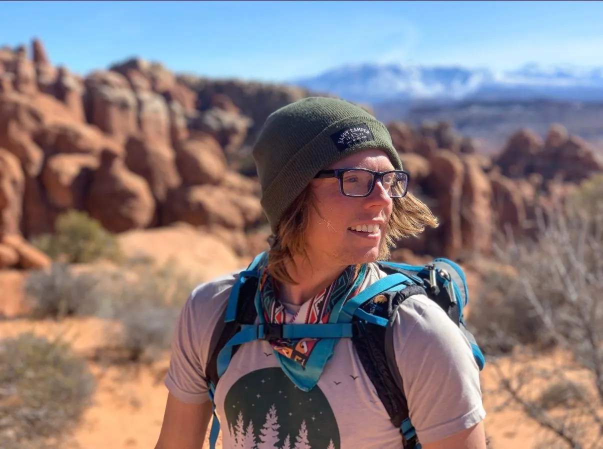 Guide JP in a beanie and glasses among Moab's red-rock fins
